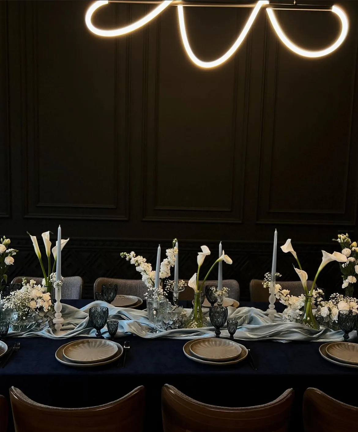 Festive table with white calla lilies, candles and a pale blue silk runner