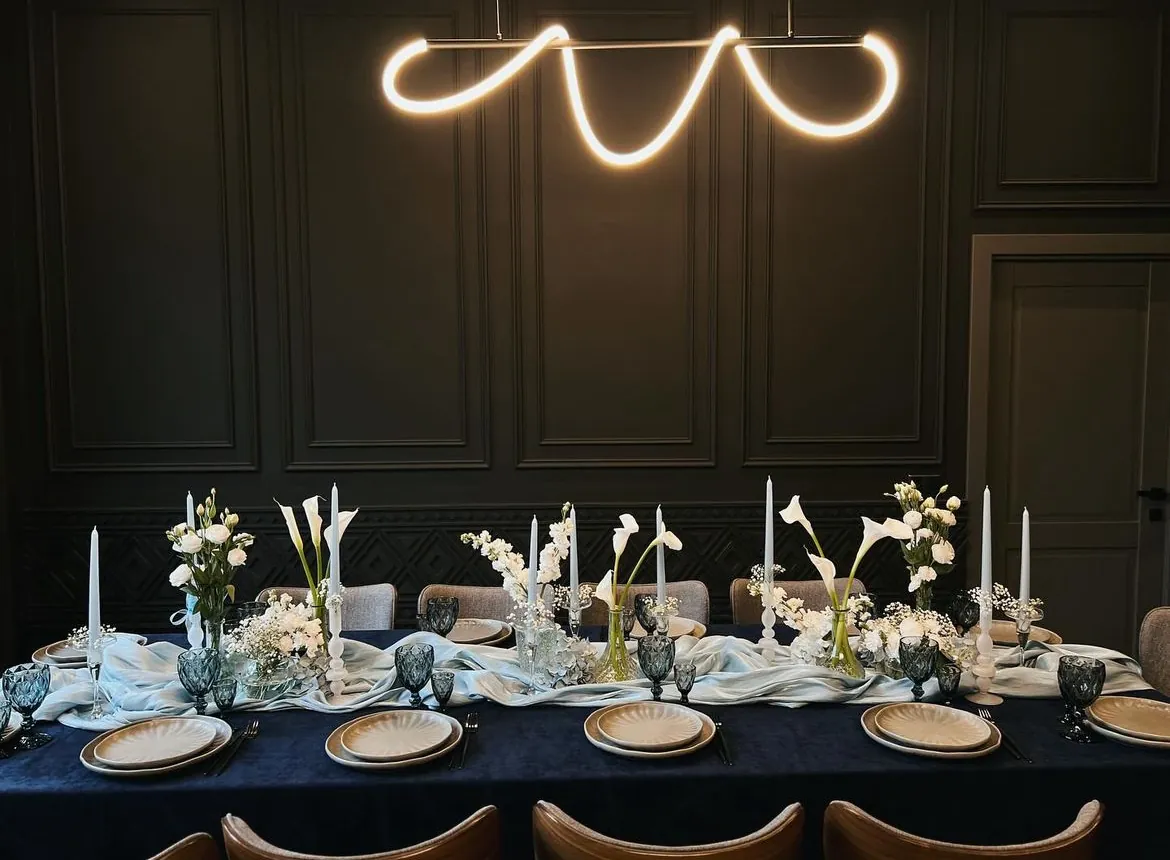 Festive table with a navy tablecloth, white calla lilies, candles and a pendant light in the Black Inn dining room