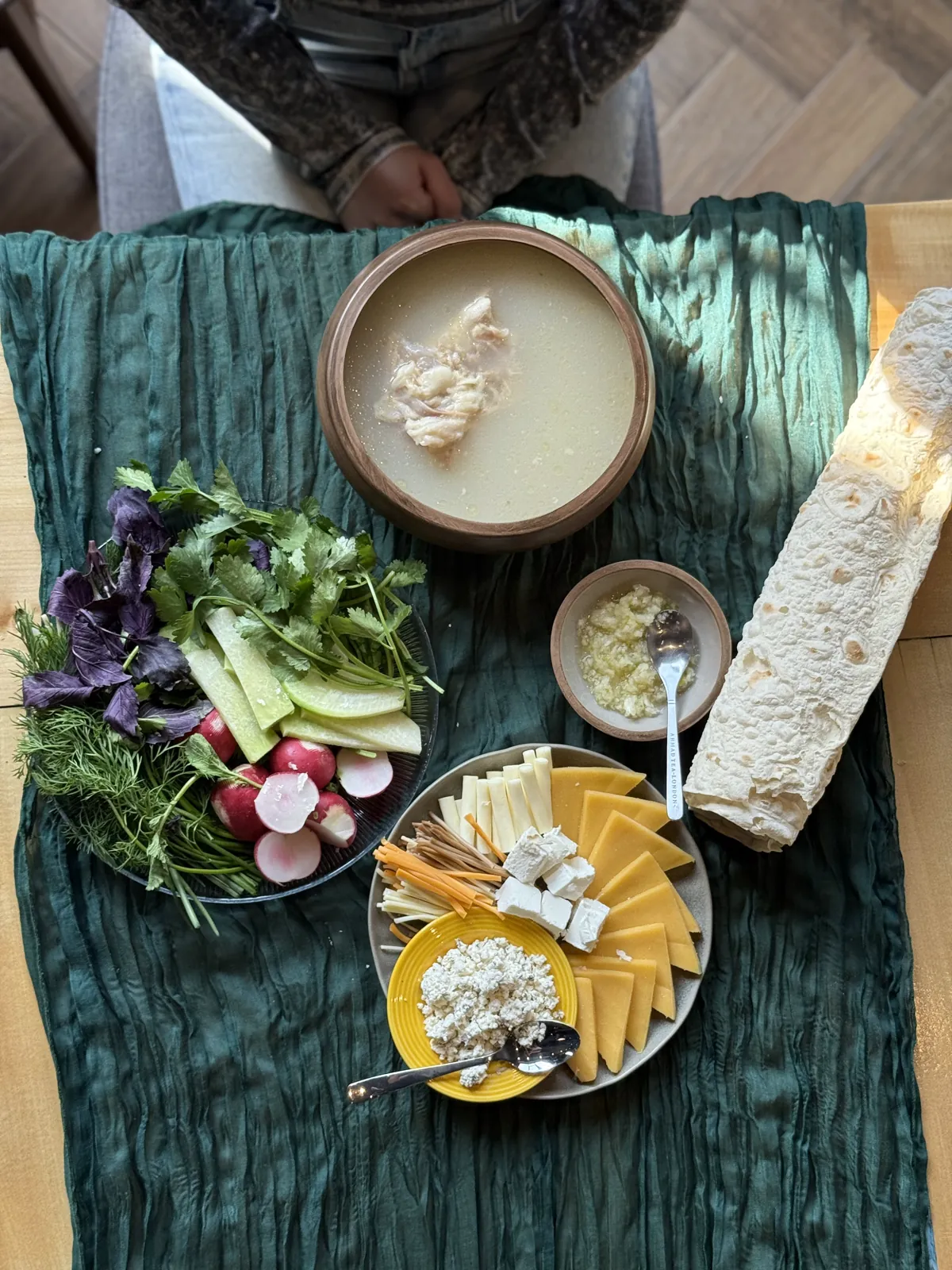 A khash table with khash, garlic, lavash, fresh herbs, radishes and cheese