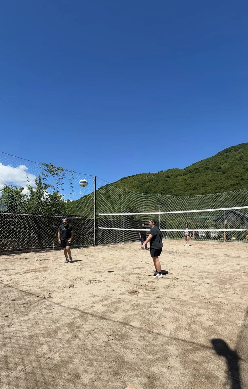 Friends playing sand volleyball under a clear blue sky