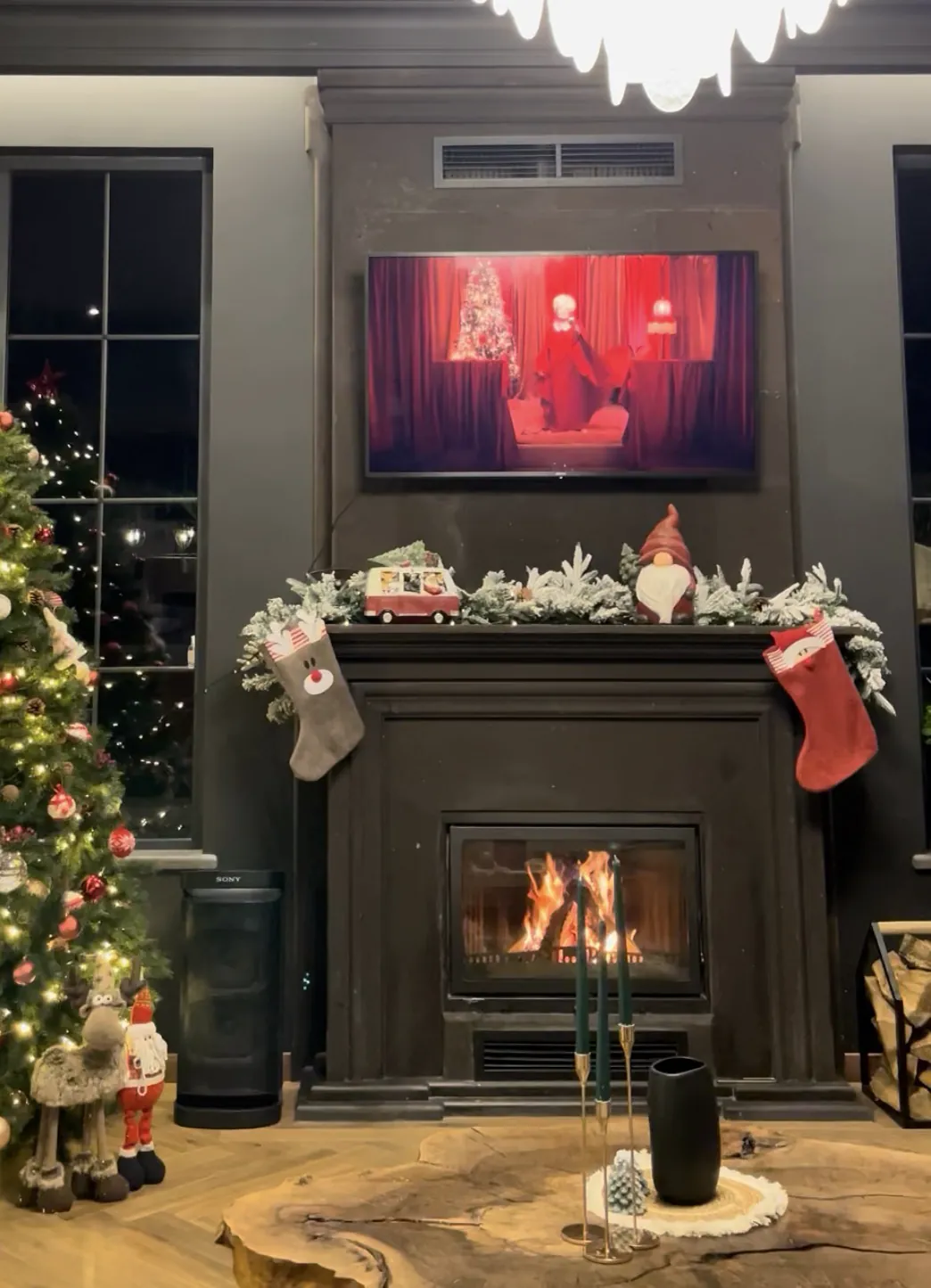 A lit fireplace in the living room with winter decorations