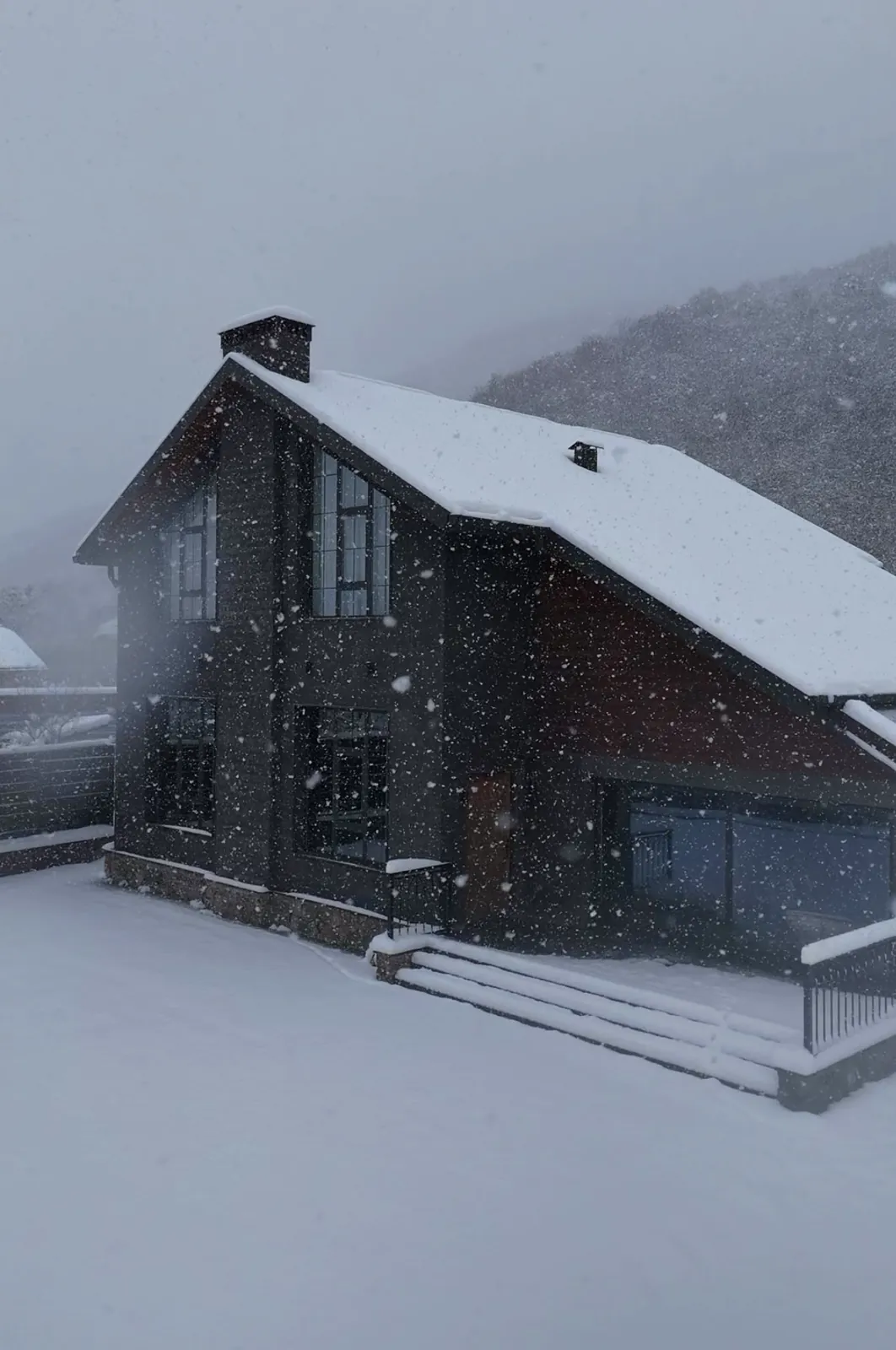 The Black Inn house under falling snow