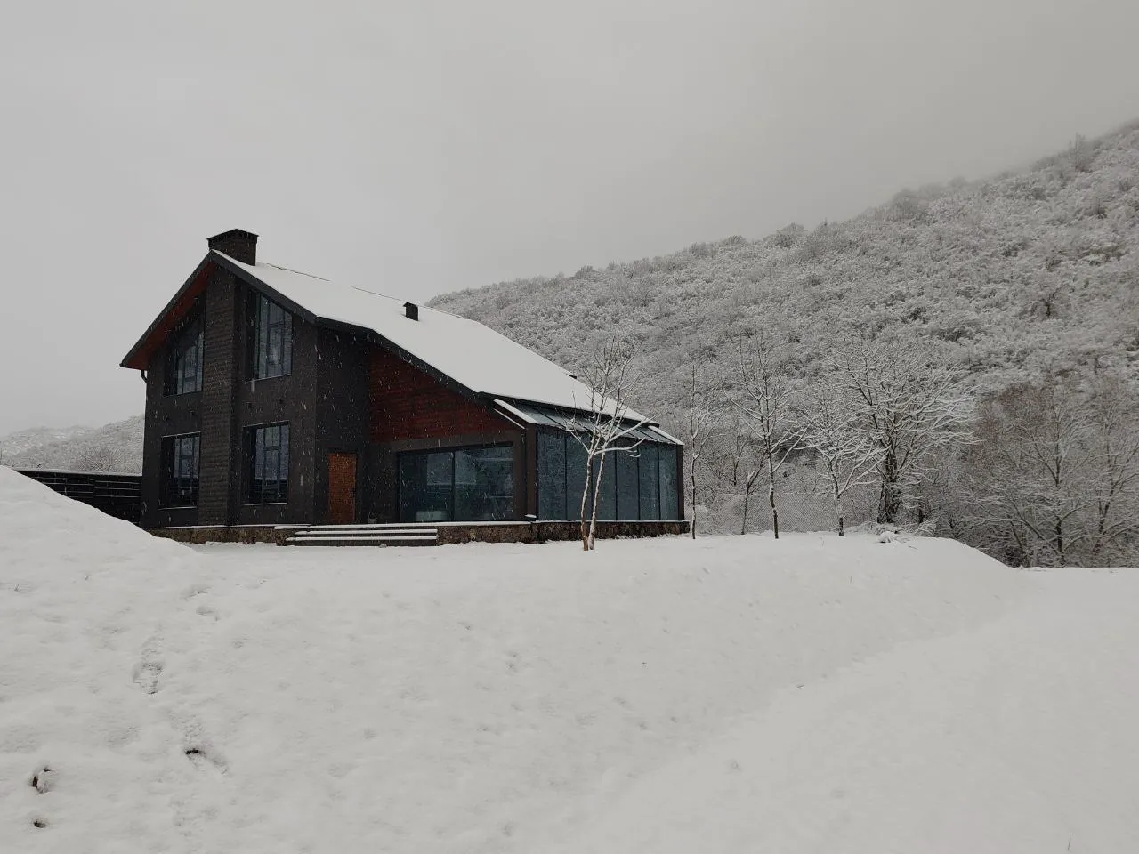 Snow-covered grounds and house against wintry hills